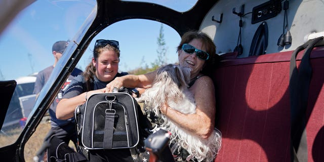 Helen Koch, a dog breeder, is evacuated with some of her 17 dogs on a helicopter for mediccorps.org, who arrived with two helicopters, paramedics and volunteers, in the aftermath of Hurricane Ian on Pine Island, Florida, Saturday, Oct. 1, 2022.