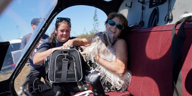 Helen Koch, a dog breeder, is evacuated with some of her 17 dogs on a helicopter for mediccorps.org, who arrived with two helicopters, paramedics and volunteers, in the aftermath of Hurricane Ian on Pine Island, Florida, Saturday, Oct. 1, 2022.