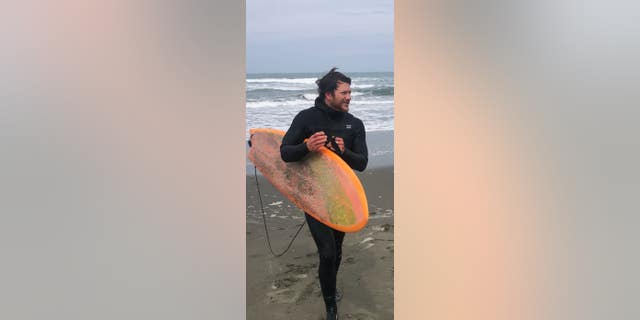 Michael Trainor posing with surfboard.
