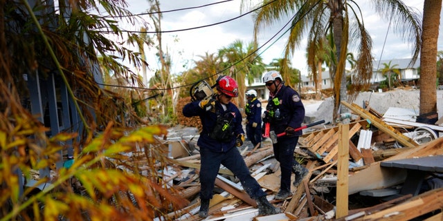 Members of Florida Task Force 2 urban search and rescue check homes and piles of debris for the presence of people or human remains, one week after the passage of Hurricane Ian, in Fort Myers Beach, Fla., Wednesday, Oct. 5, 2022. 