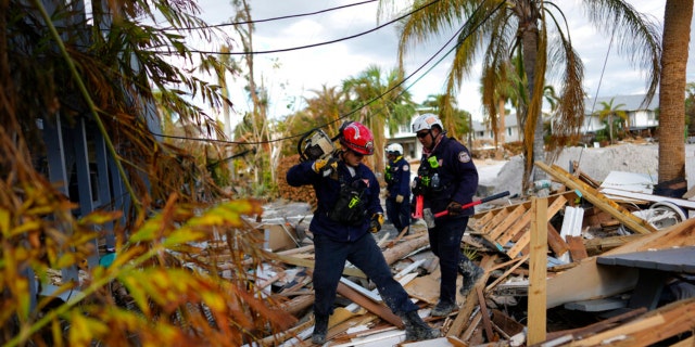 Members of Florida Task Force 2 urban search and rescue check homes and piles of debris for the presence of people or human remains, one week after the passage of Hurricane Ian, in Fort Myers Beach, Fla., Wednesday, Oct. 5, 2022.