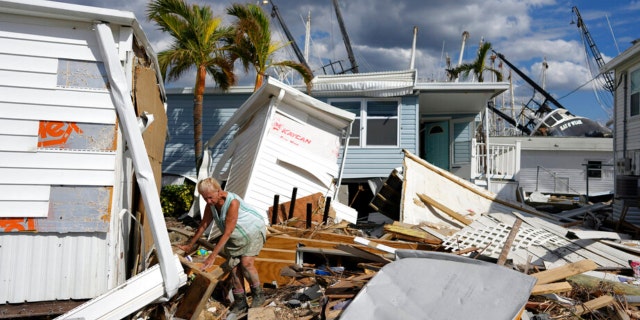 Kathy Hickey, 70, carefully picks her way through debris from destroyed trailers in the mobile home park where she and her husband Bruce had a winter home, a trailer originally purchased by Kathy's mother in 1979, on San Carlos Island in Fort Myers Beach, Fla., Wednesday, Oct. 5, 2022, one week after the passage of Hurricane Ian.