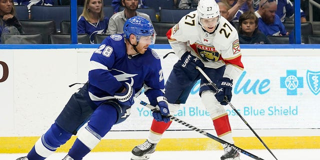 Florida Panthers center Eetu Luostarinen (27) works around Tampa Bay Lightning defenseman Ian Cole (28) during the third period of an NHL pre-season game on Saturday, October 8, 2022, in Tampa, Florida.