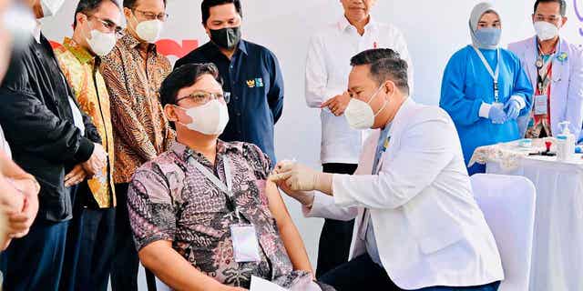Indonesia President Joko Widodo, center, watches as a medical worker administers a shot of the IndoVac COVID-19 vaccine, during the launch of the country's first home-grown COVID-19 vaccine in Bandung, West Java, Indonesia, on Oct 13, 2022.