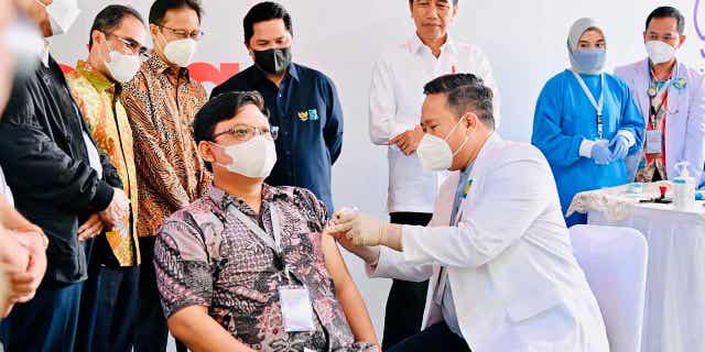 Indonesia President Joko Widodo, center, watches as a medical worker administers a shot of the IndoVac COVID-19 vaccine, during the launch of the country's first home-grown COVID-19 vaccine in Bandung, West Java, Indonesia, on Oct 13, 2022.