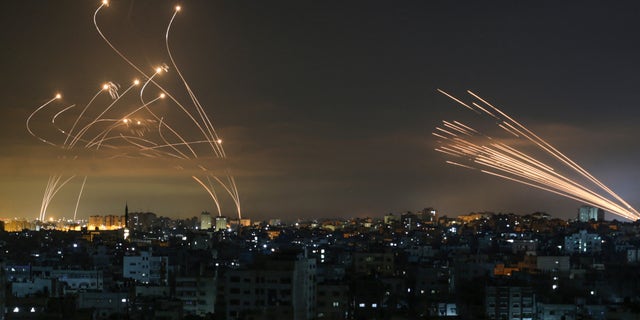 The Israeli Iron Dome missile defence system, left, intercepts rockets, right, fired by the Hamas movement towards southern Israel from Beit Lahia in the northern Gaza Strip as seen in the sky above the Gaza Strip overnight on May 14, 2021.