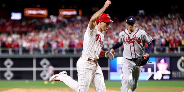 J.T. Realmuto, left, of the Philadelphia Phillies scores a run on an RBI single by Nick Castellanos against the Atlanta Braves during the seventh inning in Game 3 of the National League Division Series at Citizens Bank Park Oct. 14, 2022, in Philadelphia.