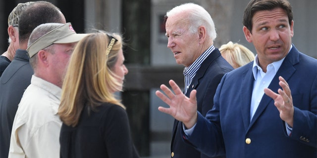 Florida Gov. Ron DeSantis, right, gestures as President Biden speaks with local residents impacted by Hurricane Ian in Fort Myers, Florida, on Oct. 5, 2022.