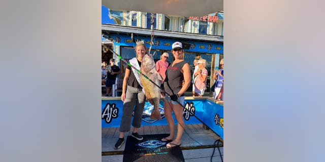 Julie Augustine (right) took her black drum catch to the Destin Fishing Rodeo in Florida for weighing on Oct. 1, 2022. Here, she holds the 37.6-pound fish and her nine-foot polespear while posing with Miss Destin 2022 (left).