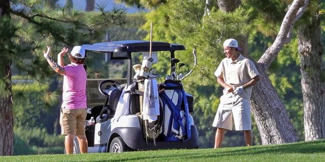 Justin Bieber talks to a man near their golf cart.