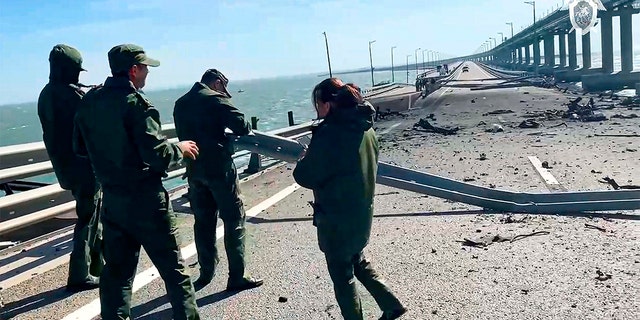 In this image taken from video released by the Russian Investigative Committee, employees of the Russian Investigative Committee work at the scene of a damaged part of the Crimean Bridge connecting Russian mainland and Crimean peninsula over the Kerch Strait, near Kerch, Crimea, Saturday, Oct. 8, 2022.