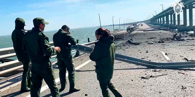 In this image taken from video released by the Russian Investigative Committee, employees of the Russian Investigative Committee work at the scene of a damaged part of the Crimean Bridge connecting Russian mainland and Crimean peninsula over the Kerch Strait, near Kerch, Crimea, Saturday, Oct. 8, 2022.