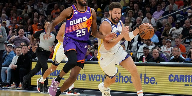 Golden State Warriors guard Klay Thompson drives past Phoenix Suns forward Mikal Bridges, #25, during the first half of an NBA basketball game, Tuesday, Oct. 25, 2022, in Phoenix. 