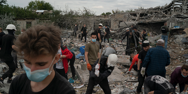 Volunteers work to clean the debris on a site where several houses were destroyed after a Russian attack at a residential area in Zaporizhzhia, Ukraine, Sunday, Oct. 9, 2022.