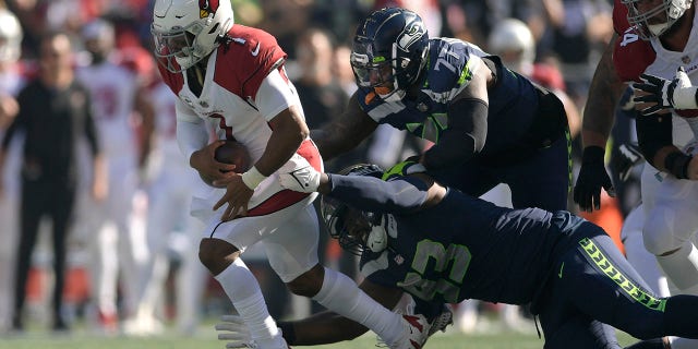 Arizona Cardinals quarterback Kyler Murray, left, runs against Seattle Seahawks defensive end Shelby Harris (93) and defensive tackle Quinton Jefferson (77) during the first half of an NFL football game in Seattle, Sunday, Oct. 16, 2022.