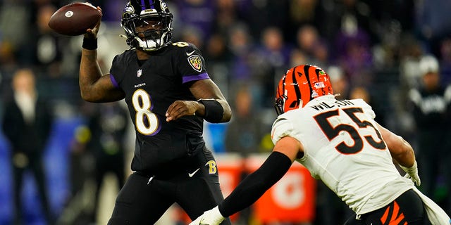 Baltimore Ravens quarterback Lamar Jackson hands the ball to Cincinnati Bengals' Logan Wilson during the second half of an NFL football game in Baltimore on Sunday, Oct. 9, 2022. 