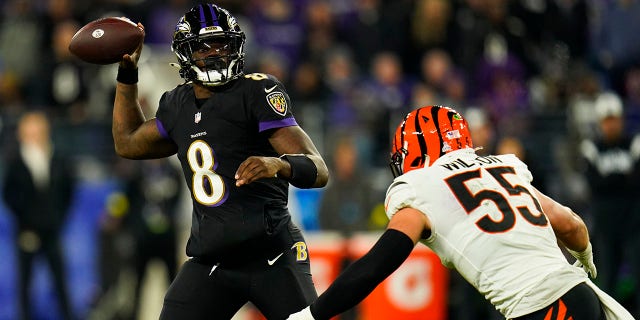 Baltimore Ravens quarterback Lamar Jackson hands the ball to Cincinnati Bengals' Logan Wilson during the second half of an NFL football game in Baltimore on Sunday, Oct. 9, 2022. 