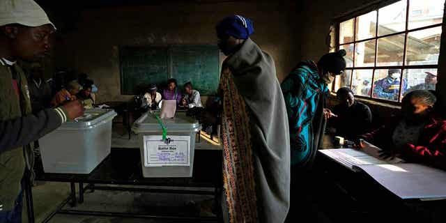 A man wearing a blanket casts his vote at a polling station in Maseru, Lesotho, on Oct. 7, 2022. Voters across Lesotho are heading to the polls Friday to elect a leader to find solutions to high unemployment and crime. 