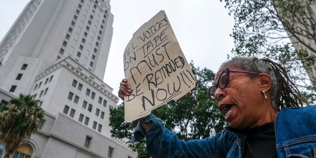 Veronica Sance holds a sign in a news conference to denounce racism and demand change in response to a recorded, racially charged leaked conversation between leaders at City Hall and the Los Angeles County Federation of Labor President, before the Los Angeles City Council meeting outside city hall Tuesday Oct. 11, 2022 in Los Angeles. 