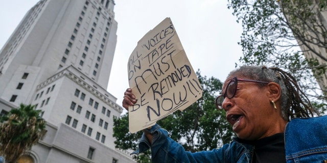 Veronica Sance holds a sign in a news conference to denounce racism and demand change in response to a recorded, racially charged leaked conversation between leaders at City Hall and the Los Angeles County Federation of Labor President, before the Los Angeles City Council meeting outside city hall Tuesday Oct. 11, 2022 in Los Angeles. 