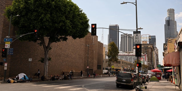 People camp in tents under a shady tree on the sidewalk near Skid Row during a heat wave in downtown Los Angeles, California on September 2, 2022.