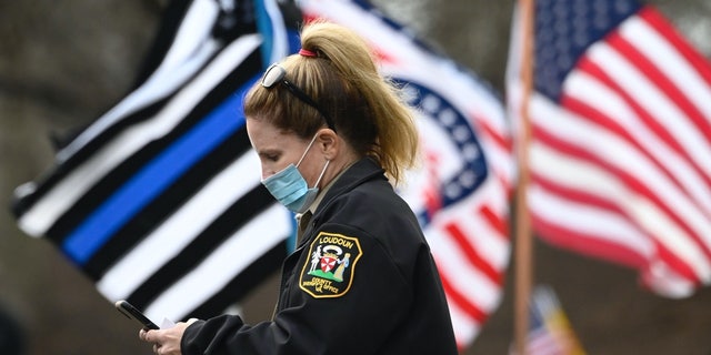 A police officer in Loudoun County, Virginia, looks at her phone in Sterling, Virginia on Nov. 22, 2020.