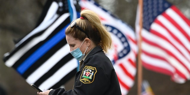 A police officer in Loudoun County, Virginia, looks at her phone in Sterling, Virginia on Nov. 22, 2020.