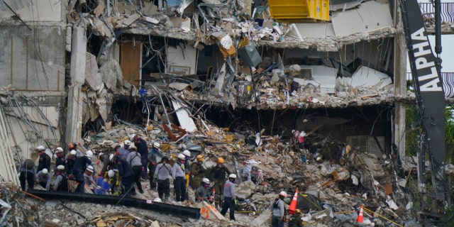 Search and rescue personnel work atop the rubble at the Champlain Towers South condo building, where scores of people remain missing after it partially collapsed the week before June 30, 2021, in Surfside, Florida.