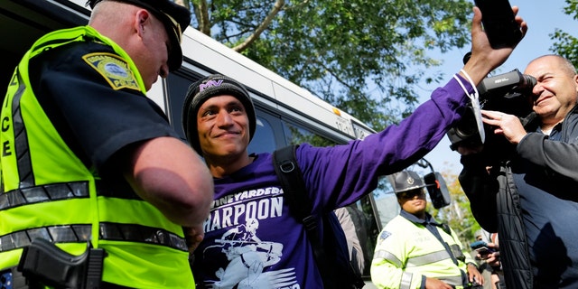 Carlos, a Venezuelan migrant, waves to volunteers before boarding a bus to the Vineyard Haven ferry terminal outside of St. Andrew's Parish House at Martha's Vineyard, Massachusetts, Sept.  16. Two plans of migrants from Venezuela arrived suddenly two days prior causing the local community to mobilize and create a makeshift shelter at the church. 