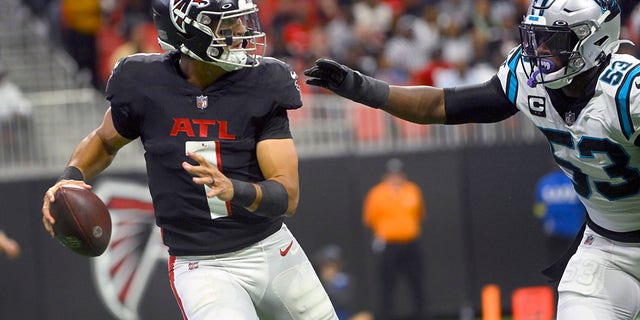 Atlanta Falcons quarterback Marcus Mariota (1) scrambles under pressure from Carolina Panthers defensive end Brian Burns during the first half, Oct. 30, 2022, in Atlanta.