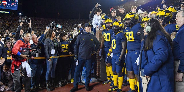 Head coach Jim Harbaugh, Mike Morris #90, Mike Sainristil #0, and Mazi Smith #58 of the Michigan Wolverines prepare to take the field before a college football game against the Michigan State Spartans at Michigan Stadium on October 29, 2022 in Ann Arbor, Michigan.