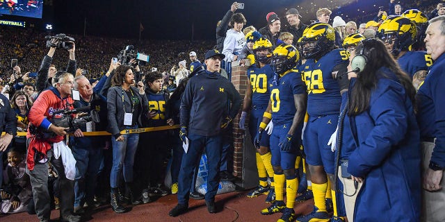 Head coach Jim Harbaugh, Mike Morris #90, Mike Sainristil #0, and Mazi Smith #58 of the Michigan Wolverines prepare to take the field before a college football game against the Michigan State Spartans at Michigan Stadium on October 29, 2022 in Ann Arbor, Michigan.