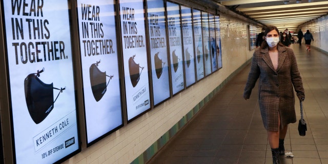 Subway passengers pass an advertisement for face masks at Manhattan's Times Square Station during the ongoing global outbreak of the novel coronavirus disease (COVID-19) in New York City, USA, November 14, 2020. 