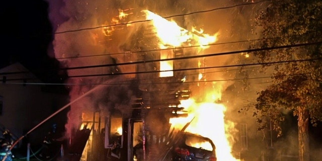 Se ve a un bombero luchando contra un gran incendio en un granero en Wappinger, Nueva York, después de que un conductor de 17 años se estrellara contra el edificio y se incendiara.