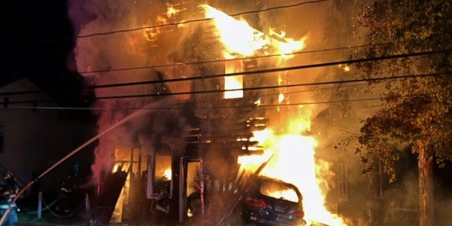 A firefighter is seen battling a large fire at a barn in Wappinger, N.Y. after a 17-year-old driver crashed into the building, causing it to erupt into flames.