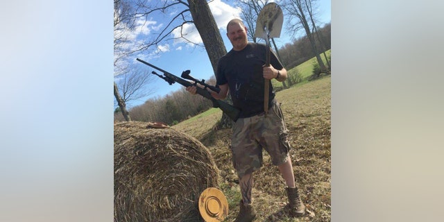 Nicholas Brutcher poses holding a gun