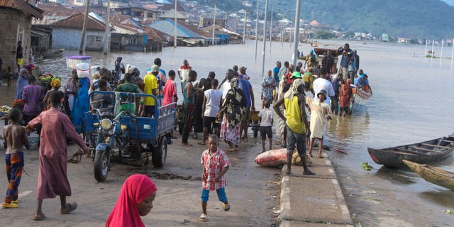 FILE- People stranded due to floods following several days of downpours In Kogi Nigeria, on Oct. 6, 2022. Nigerian state gas company has declared a force majeure after floods hindered gas operations, raising concerns among analysts about the West African nation's capacity to meet local and international demands. (AP Photo/Fatai Campbell, File)