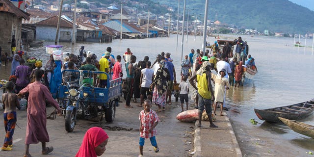 FILE- People stranded due to floods following several days of downpours In Kogi Nigeria, on Oct. 6, 2022. Nigerian state gas company has declared a force majeure after floods hindered gas operations, raising concerns among analysts about the West African nation's capacity to meet local and international demands. (AP Photo/Fatai Campbell, File)