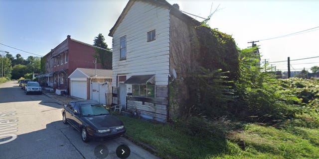 Abandoned building being taken over by surrounding vegetation.  Oliver St., Braddock, Pa.