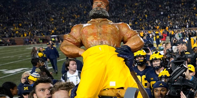 Mike Sainlistill of Michigan carries the Paul Bunyan Trophy after the Michigan State University game in Ann Arbor on Saturday, Oct. 29, 2022.