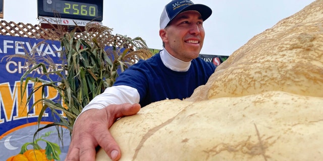 Travis Gienger from Anoka, Minnesota, embraces his winning pumpkin at the 49th World Championship Pumpkin Weigh-Off in Half Moon Bay, California, Monday, Oct. 10, 2022. 