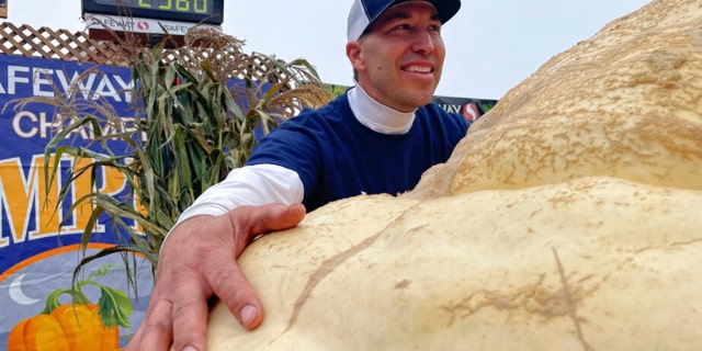 Travis Gienger from Anoka, Minnesota, embraces his winning pumpkin at the 49th World Championship Pumpkin Weigh-Off in Half Moon Bay, California, Monday, Oct. 10, 2022.