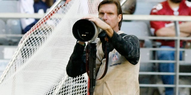 Former MLB pitcher Randy Johnson photographs an NFL game between the Dallas Cowboys and Arizona Cardinals in Glendale, Arizona, Dec. 4, 2011.