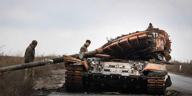 Ukrainian soldiers inspect a damaged Russian tank on a road near the recently retaken village of Kamianka, Kharkiv region, Ukraine, Sunday