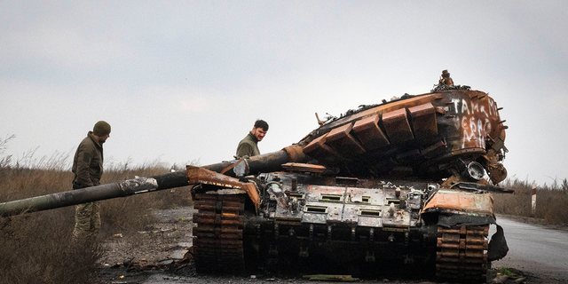 Ukrainian soldiers inspect a damaged Russian tank on a road near the recently recaptured village of Kamianka in the Kharkiv region of Ukraine on Sunday