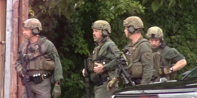 Police prepare to enter the hotel where a man was found shot to death in Poughkeepsie, New York, on Oct. 2, 2022.