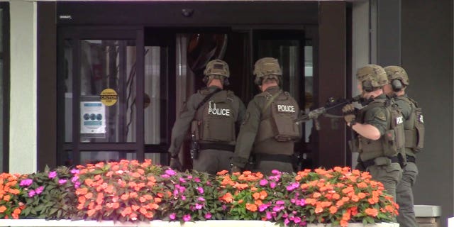 Police enter the hotel where a man was found shot to death in Poughkeepsie, New York, Sunday Oct. 2, 2022.