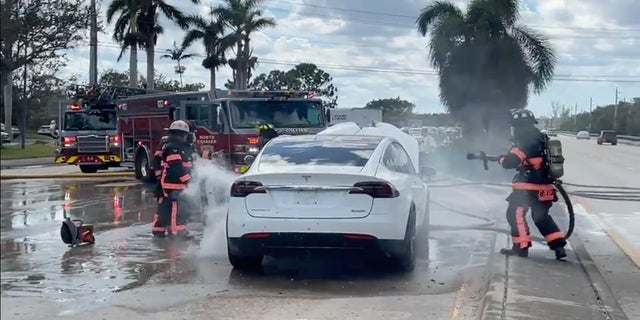 Firefighters attempt to put out a fire started from a waterlogged electric vehicle after Hurricane Ian slammed Florida's west coast.