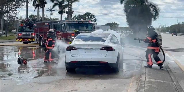 Firefighters try to put out a fire started by a flooded electric vehicle after Hurricane Ian hit Florida's west coast.