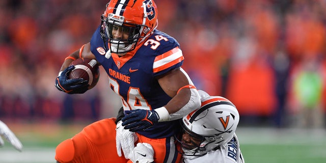 Syracuse running back Sean Tucker (34) is tackled by Virginia linebacker Chico Bennett Jr. (15) during the first half of an NCAA college football game Friday, Sept. 23, 2022, in Syracuse, N.Y.